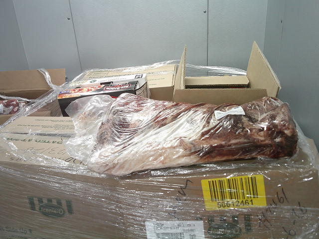 Frozen pizzas and rack of meat on top of boxes of some Jennie-O turkey product.